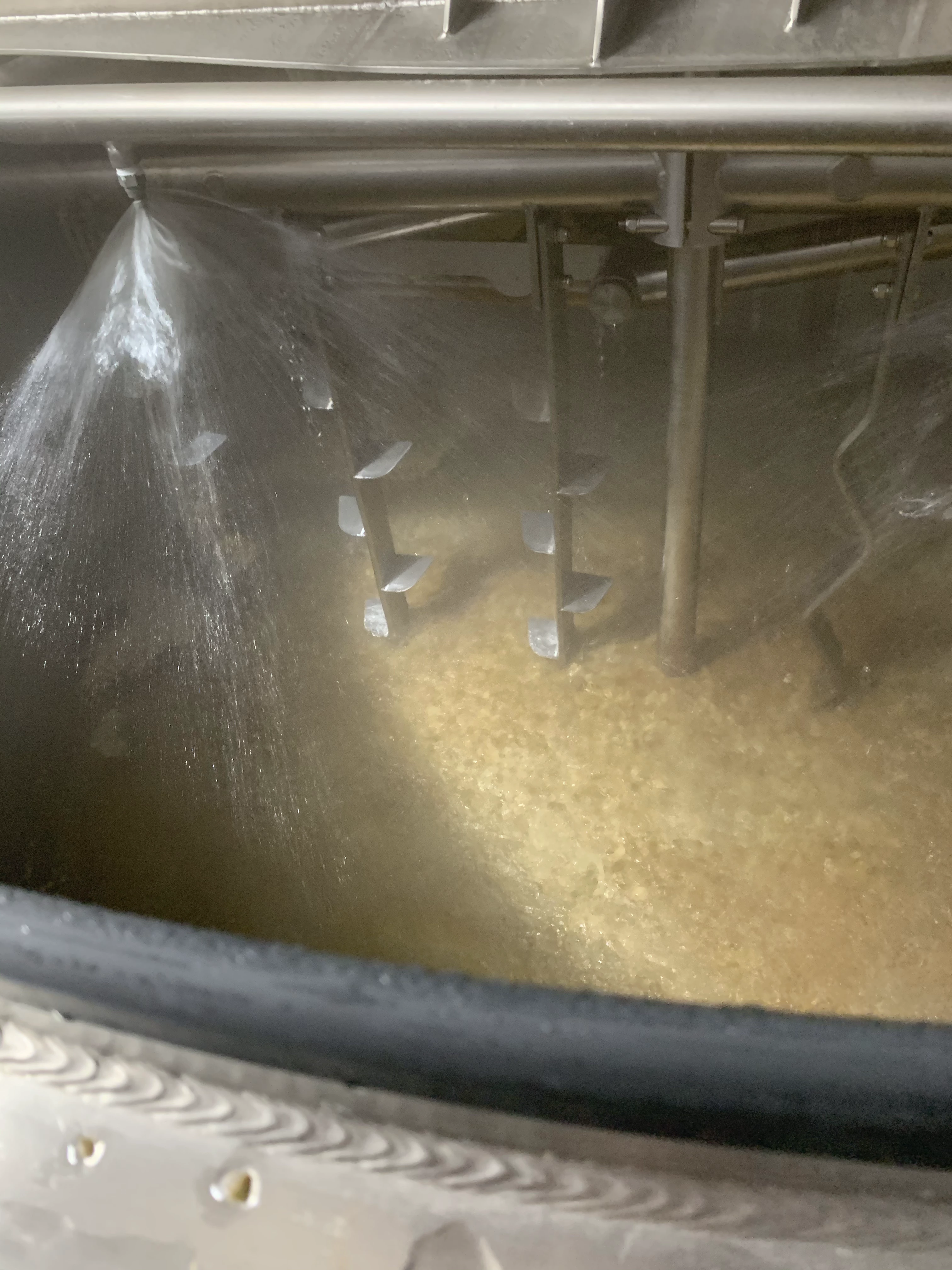 Liquid circulating inside a stainless tank viewed through the manway